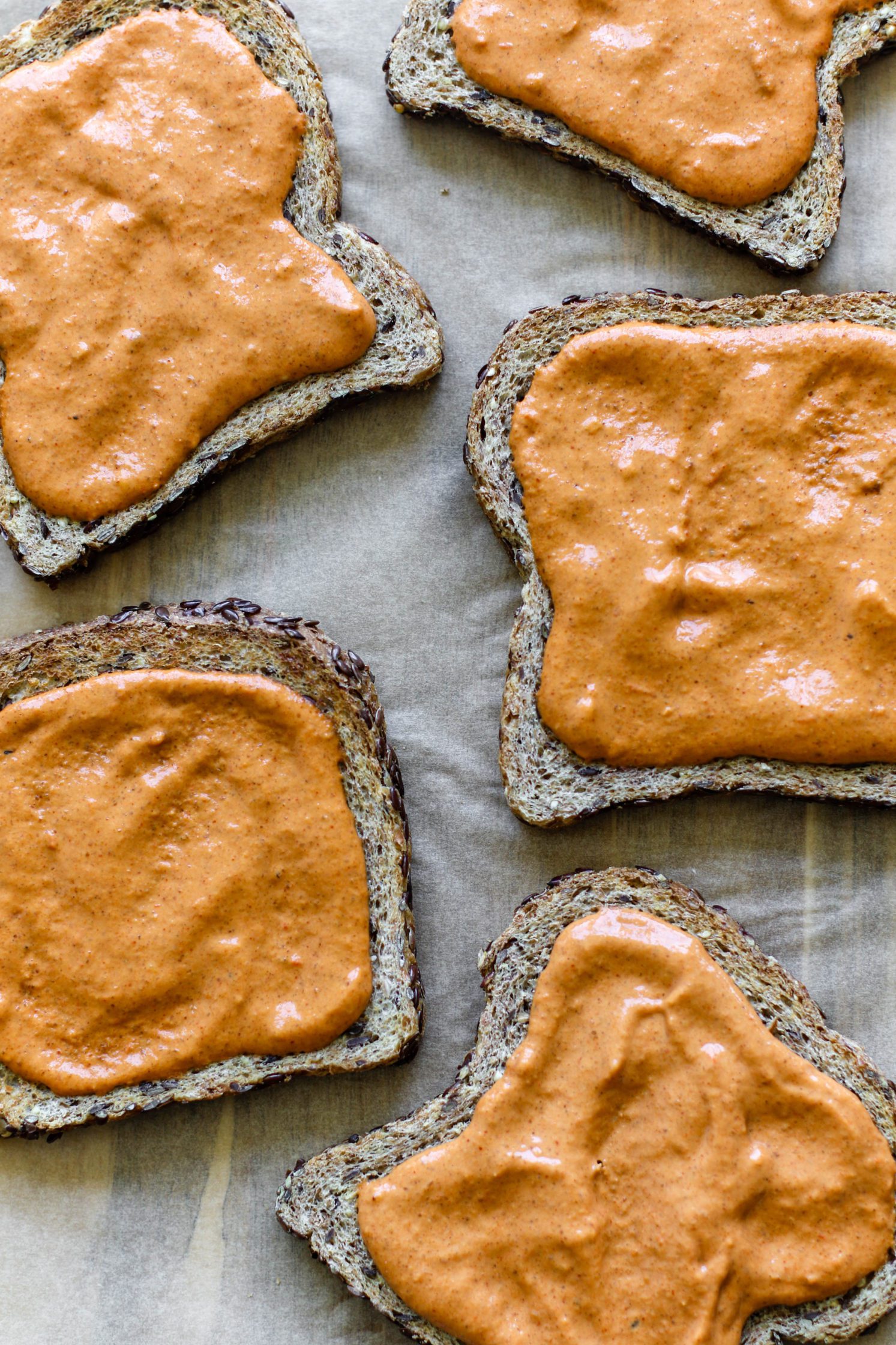 toasted bread on parchment paper topped with romesco sauce 