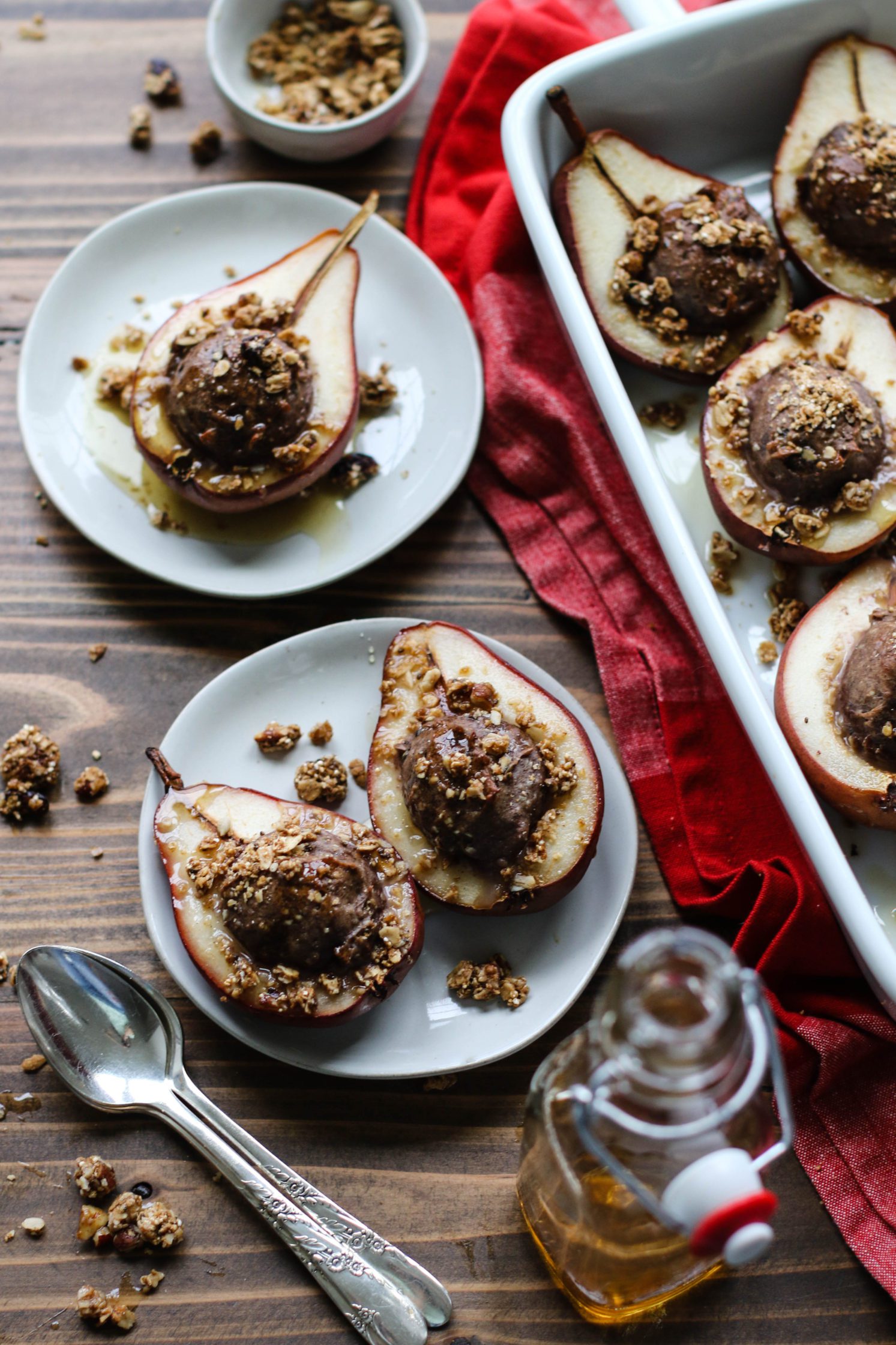 Nutty Protein Stuffed Pears served on plates with baking dish and spoons by Flora & Vino