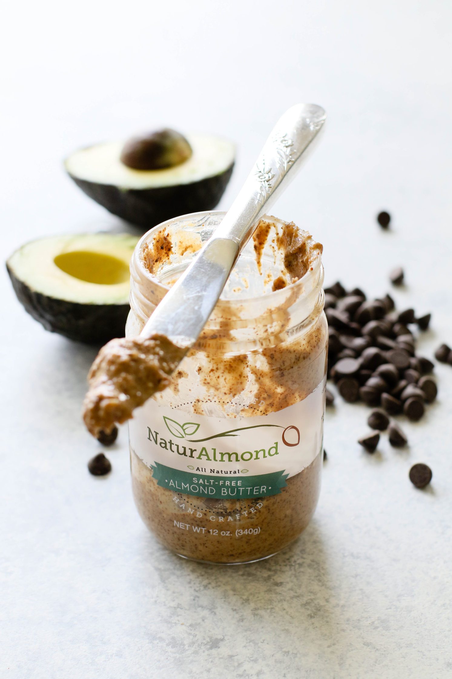 jar of almond butter with halved avocado and scattered chocolate chips