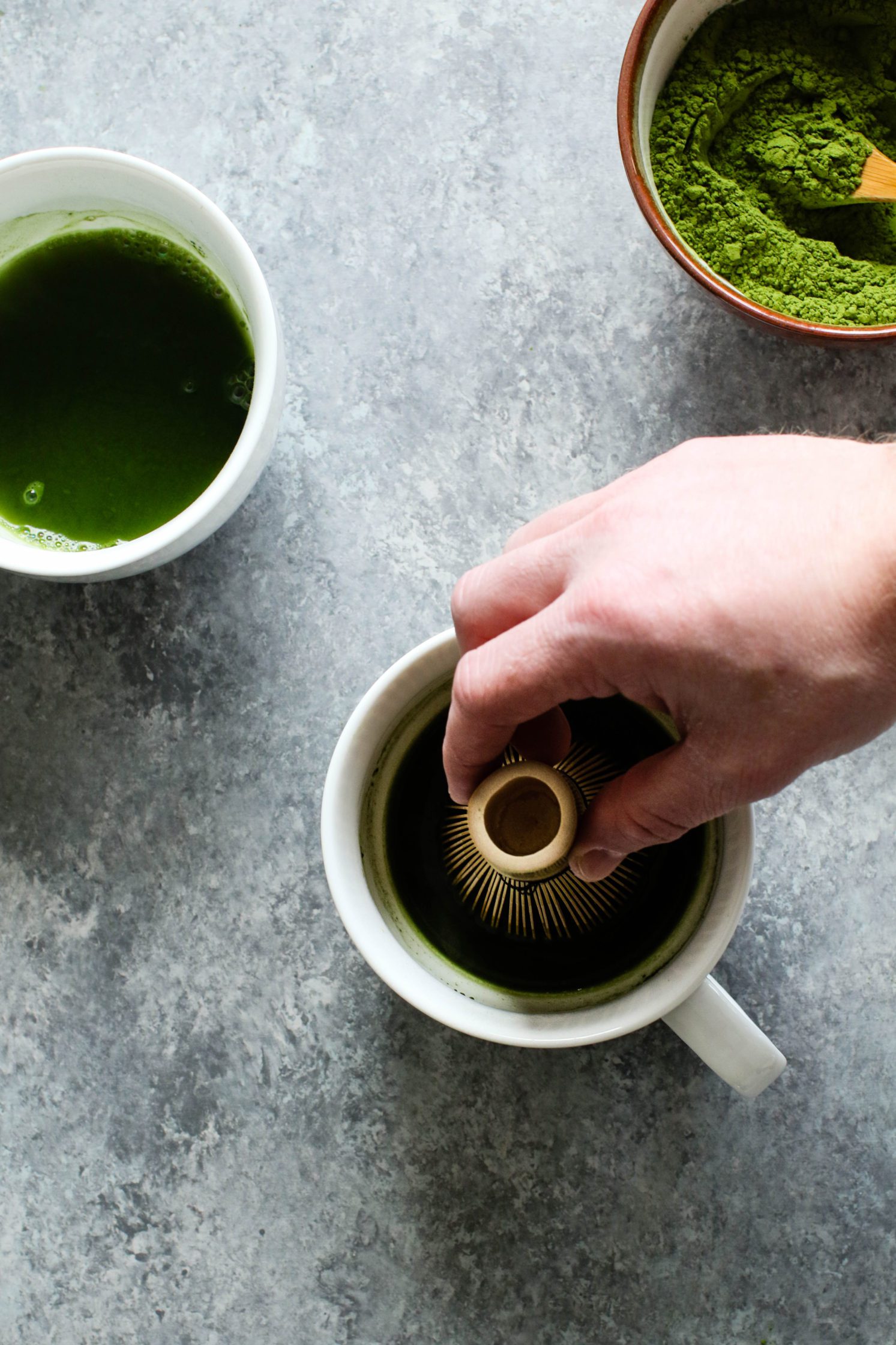 Hand whisking matcha in mugs by Flora & Vino