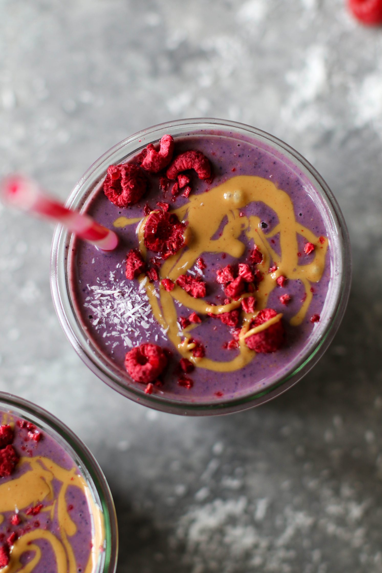 Peanut Butter Jelly & Beet Shakes served in mason jars topped with peanut butter and freeze-dried raspberries with straws.