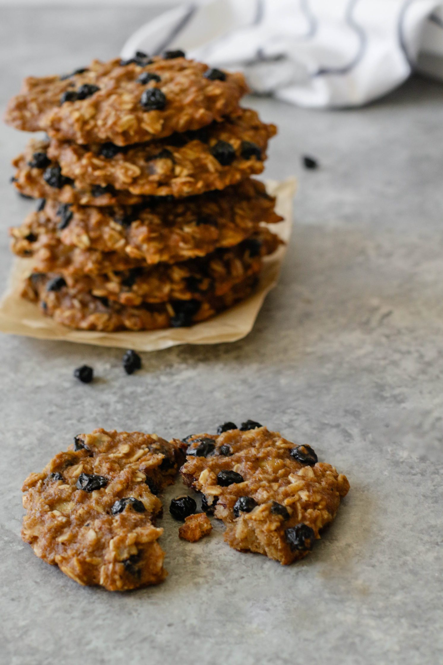 Blueberry Banana Breakfast Cookies stacked on parchment paper with one cookie broken open in front