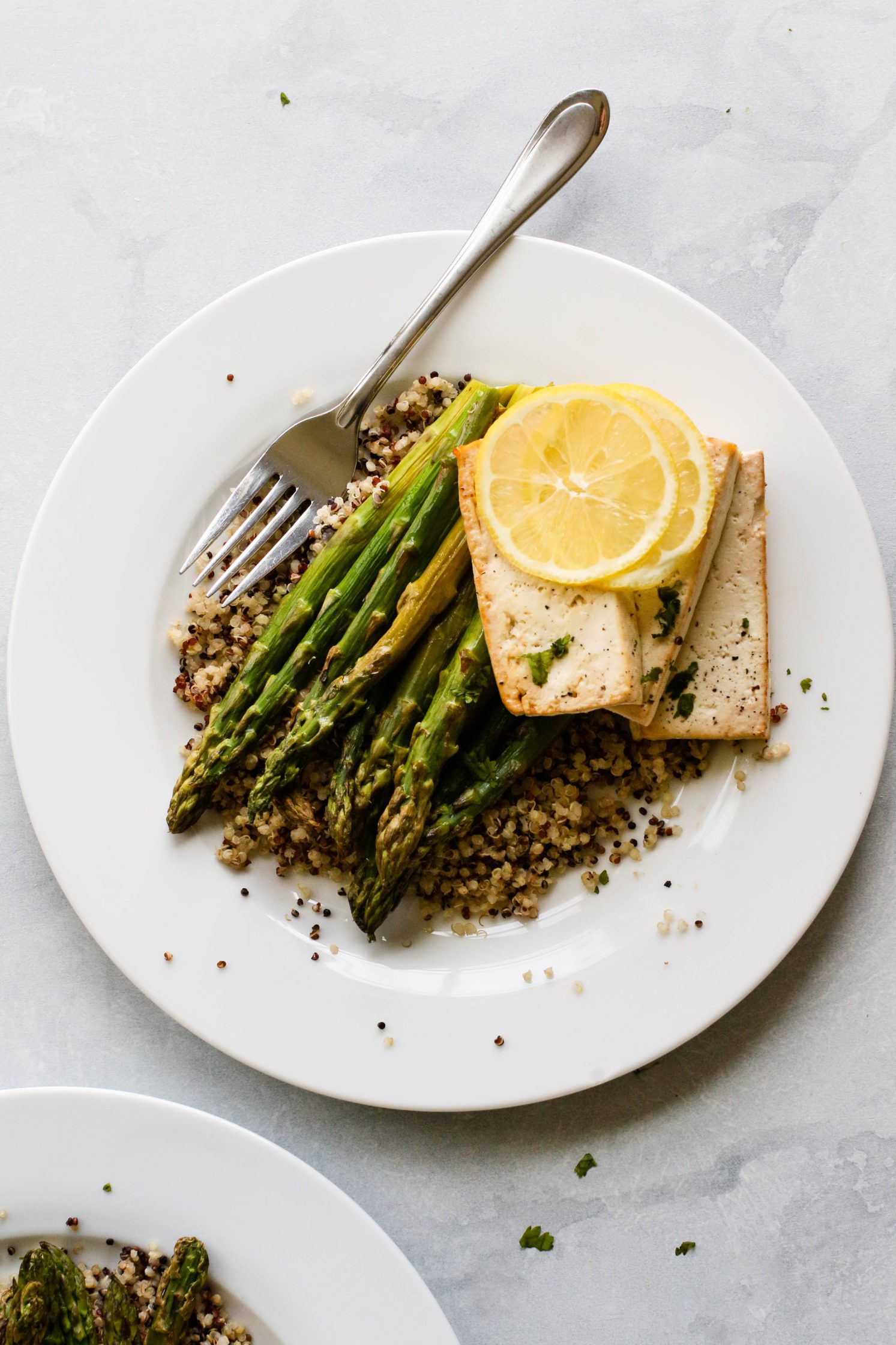 Lemon Pepper Tofu "Steaks" served on plates over quinoa with roasted asparagus and forks 