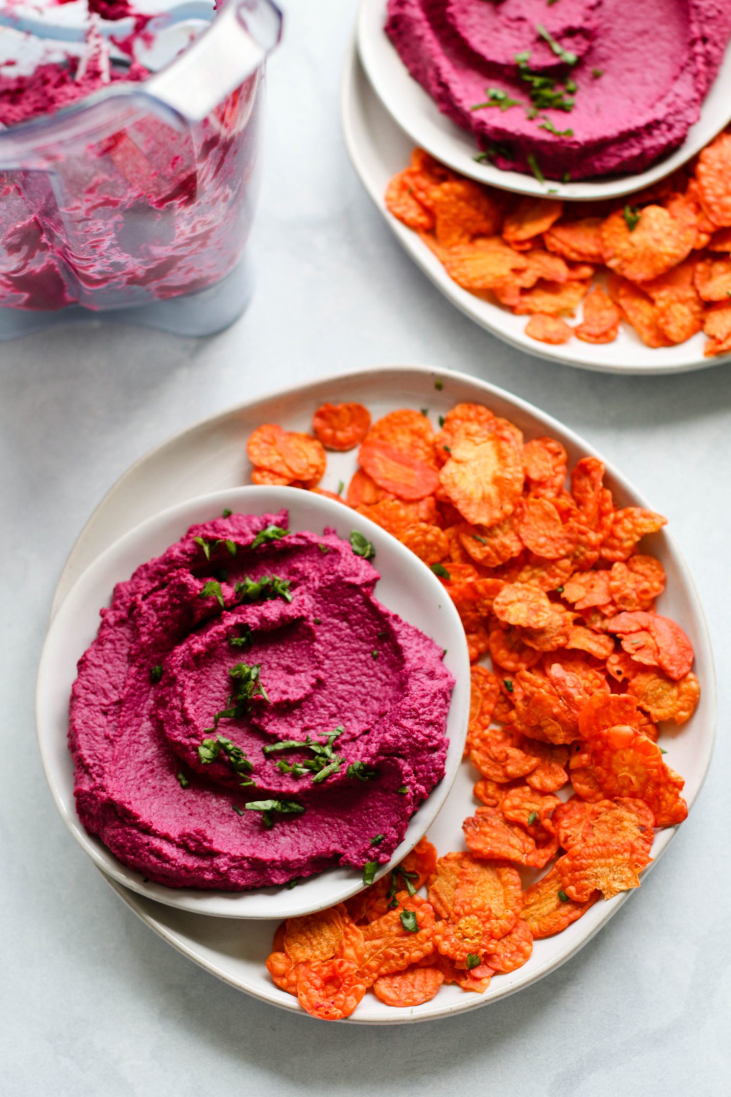 Easy Beet Hummus (Oil-Free!) served in bowl with parsley and carrots chips by Flora & Vino