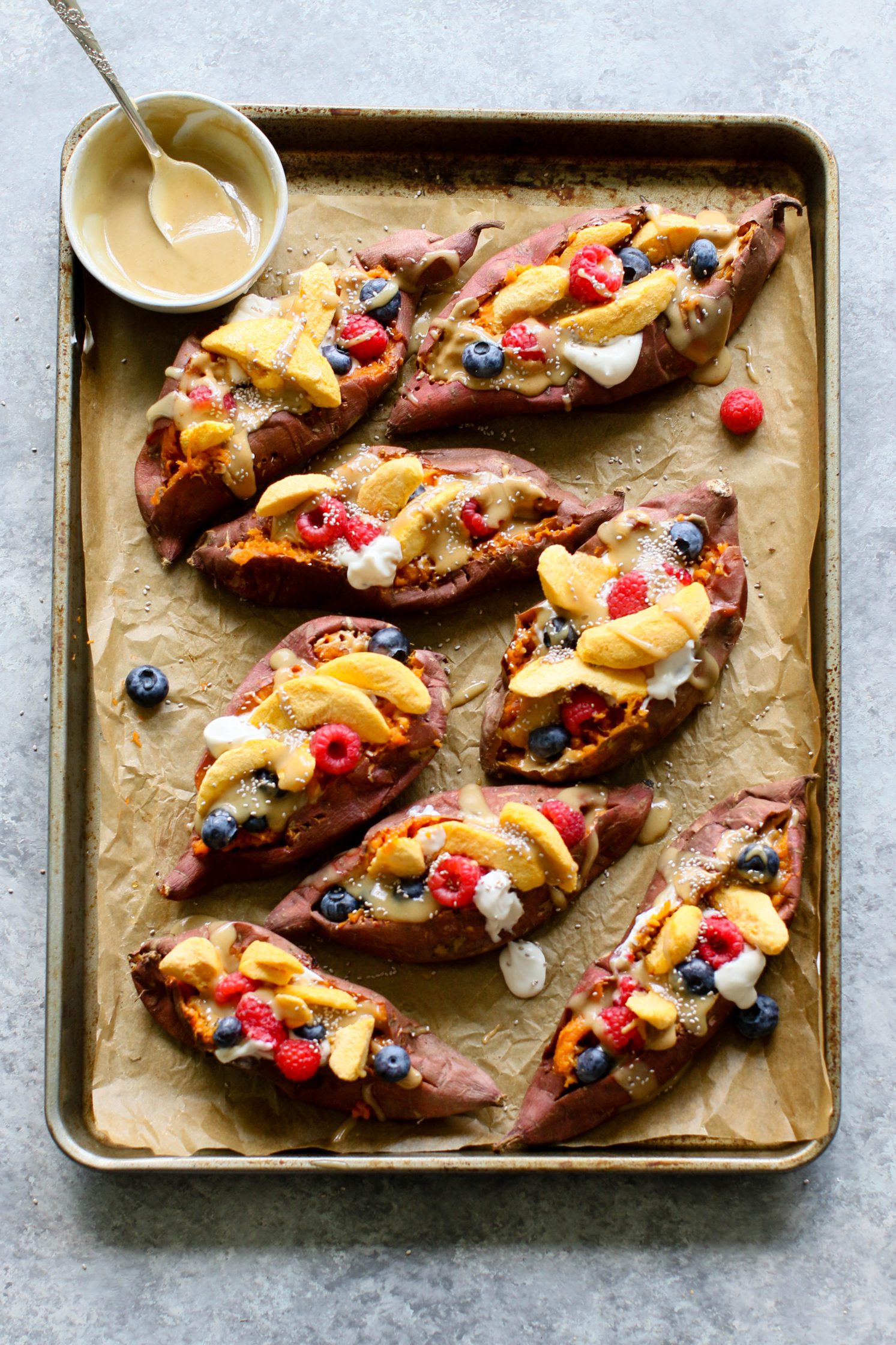 Stone Fruit Stuffed Sweet Potatoes served on parchment lined baking sheet with Maple Tahini
