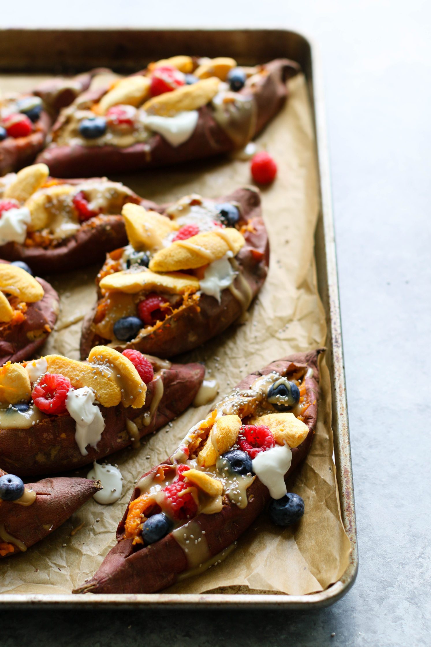 Stone Fruit Stuffed Sweet Potatoes served on parchment lined baking sheet with Maple Tahini
