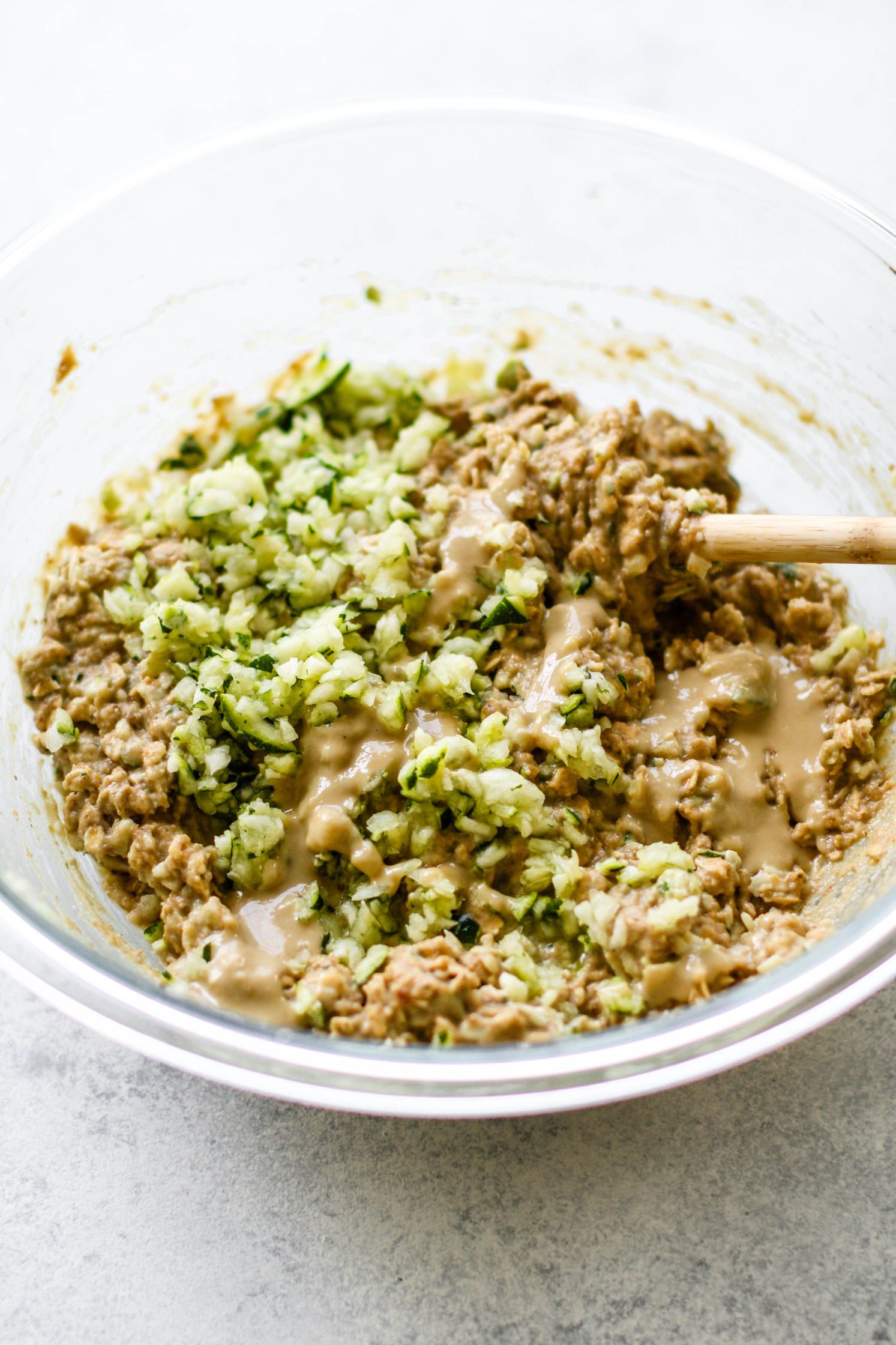 Zucchini Tahini Breakfast Cookie ingredients mixed in bowl with wooden spoon