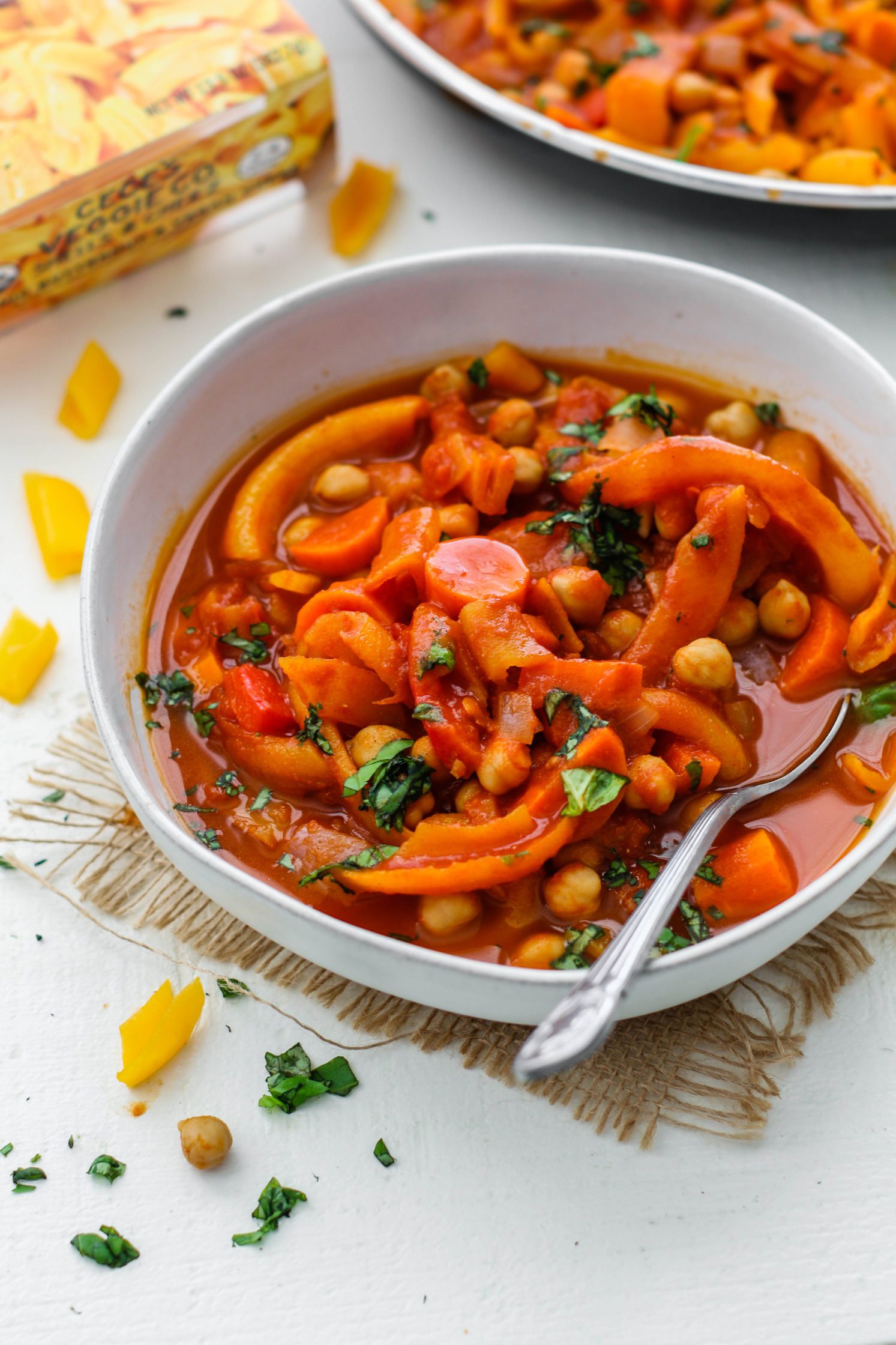 5-Spice Squash & Chickpea Stew served in bowl topped with herbs with spoon