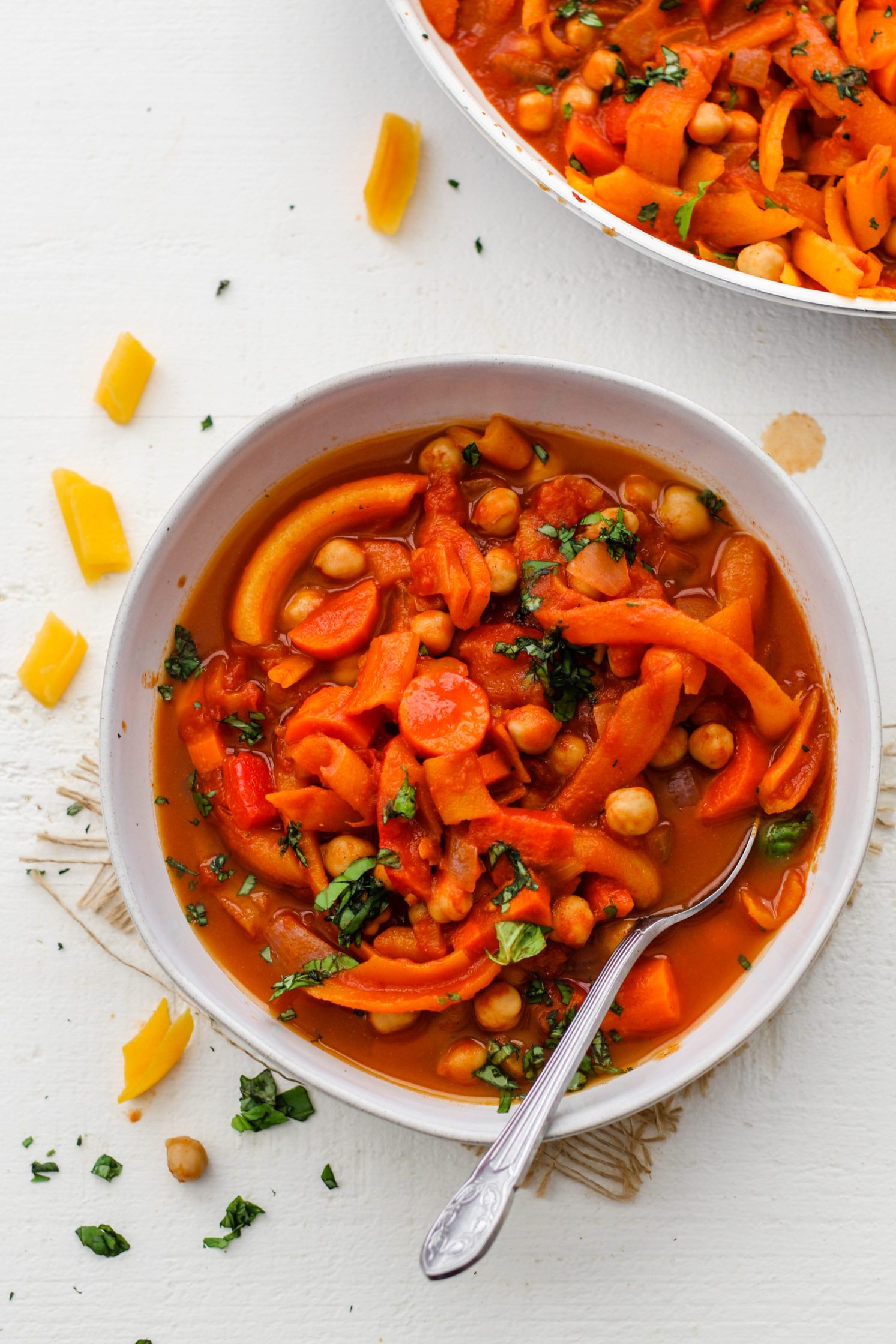5-Spice Squash & Chickpea Stew served in bowl topped with herbs with spoon