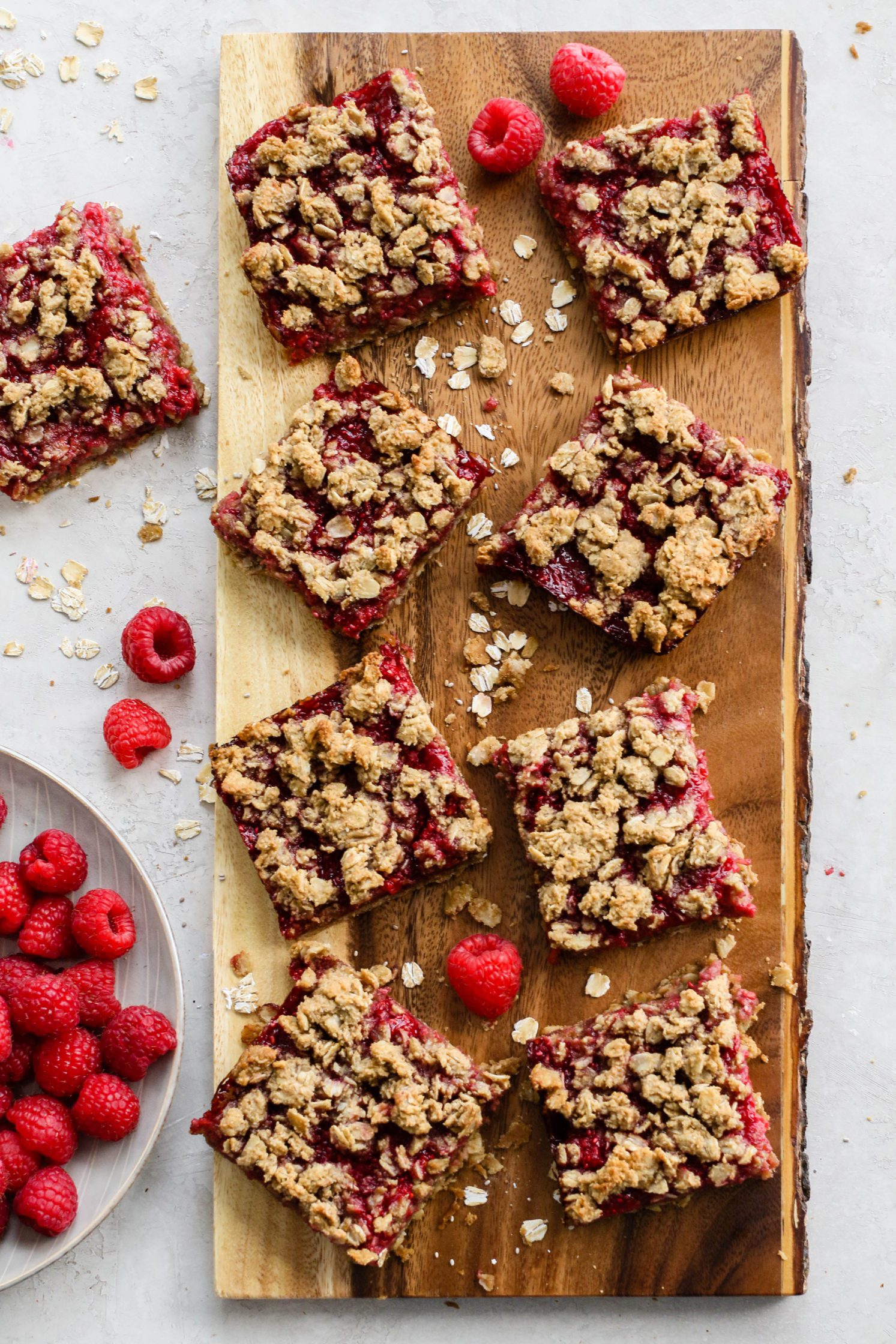 Baked Raspberry Oat Crumble Bars cut into squares on wooden board by Flora & Vino