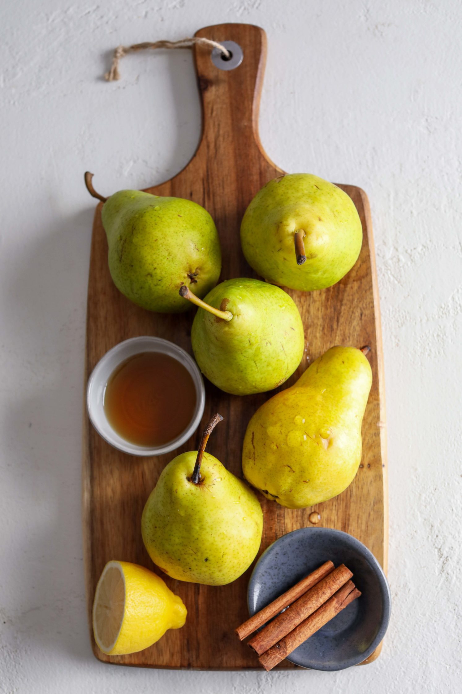 pears on cutting board with maple syrup, lemon, and cinnamon by Flora & Vino