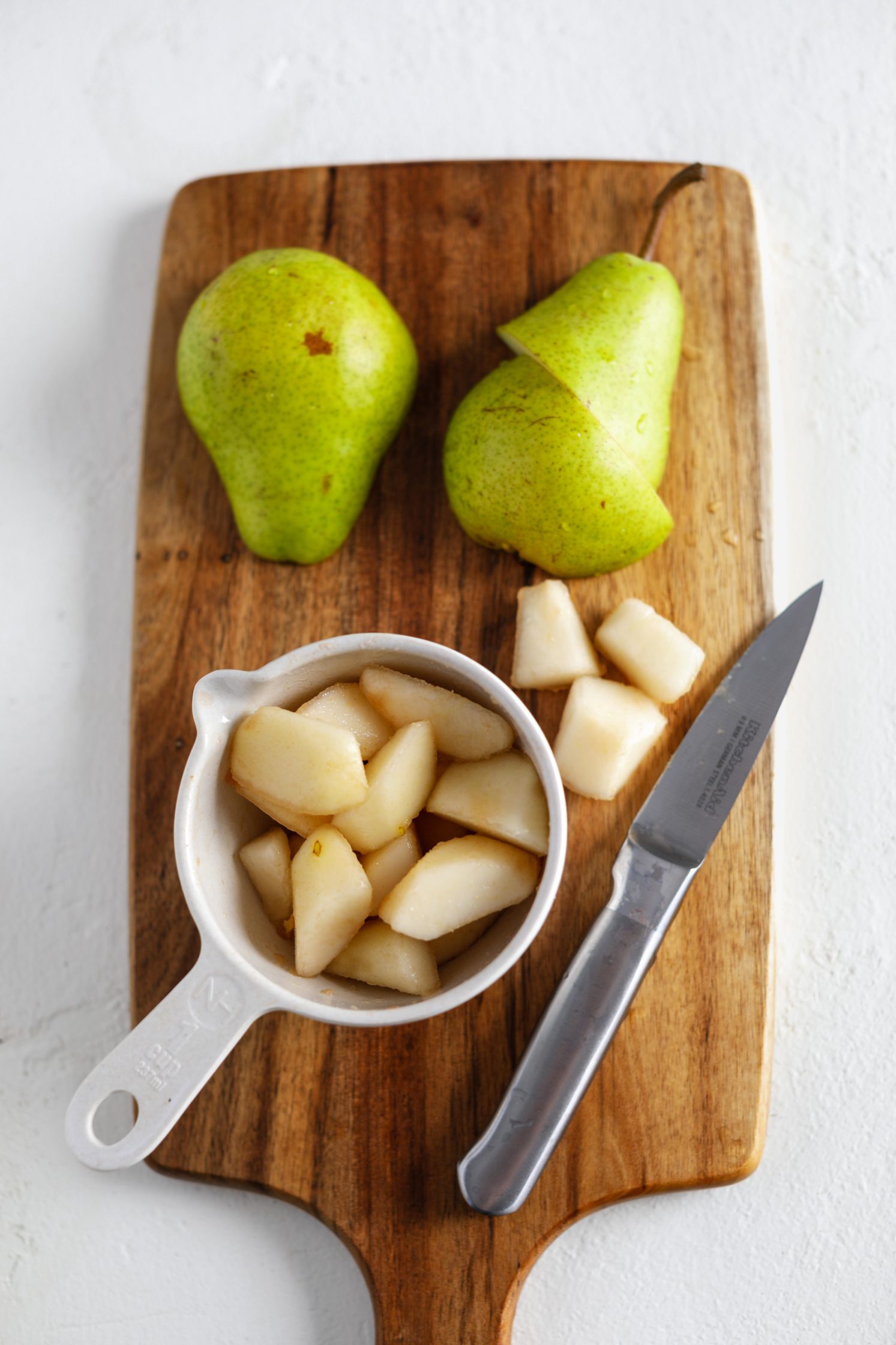 diced pear with a knife on cutting board by Flora & Vino
