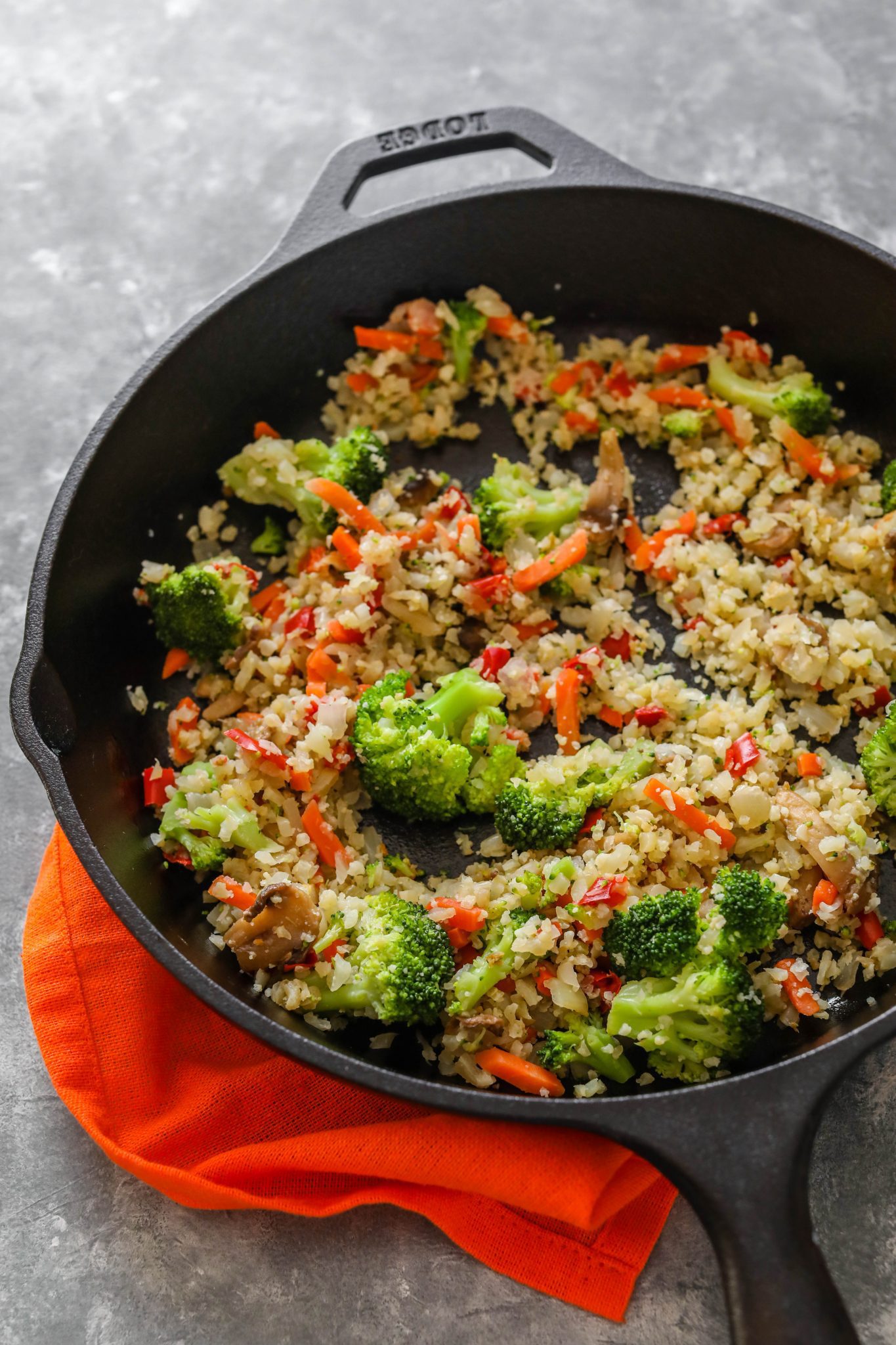 cauliflower rice in cast iron skillet on orange towel