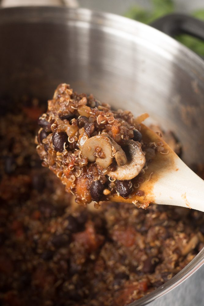 spoon serving Black Bean Quinoa Chili out of stock pot by Flora & Vino