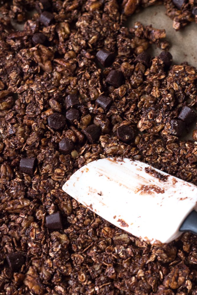 Chocolate Almond Butter Granola pressed into parchment paper with spatula by Flora & Vino