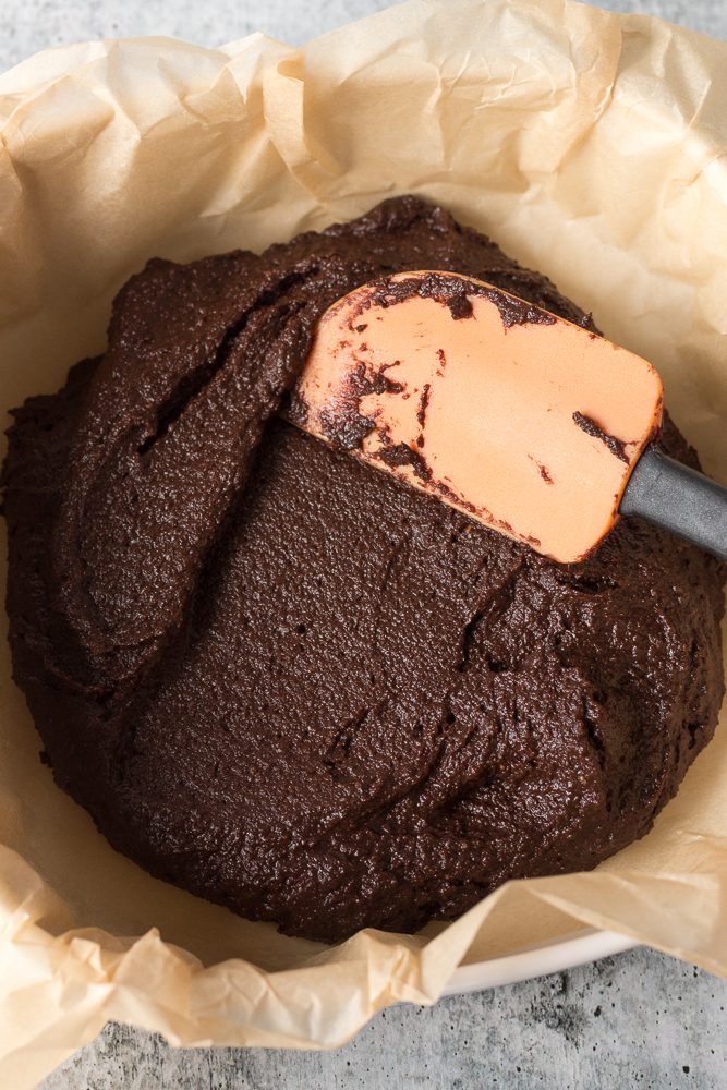 brownies batter in parchment lined baking pan and spatula by Flora & Vino