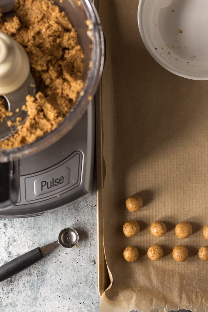 Vegan Peanut Butter balls rolled on parchment lined baking sheet by Flora & Vino
