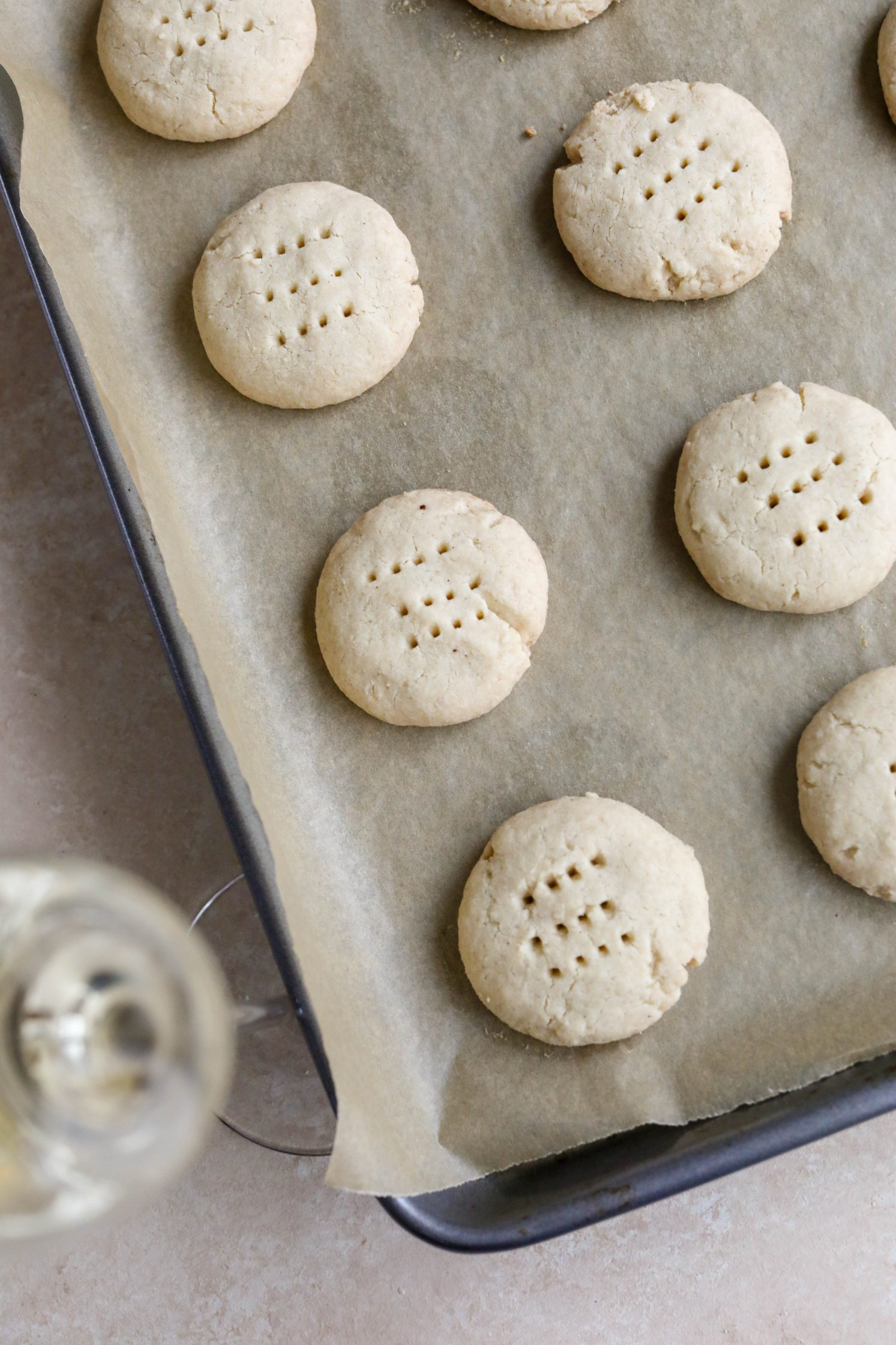 Vegan Shortbread Cookies baked on parchment paper with a glass of prosecco by Flora & Vino