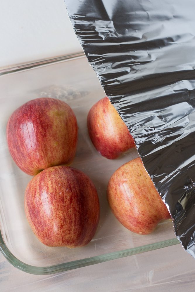 Halved apples in baking dish covered with aluminum foil by Flora & Vino