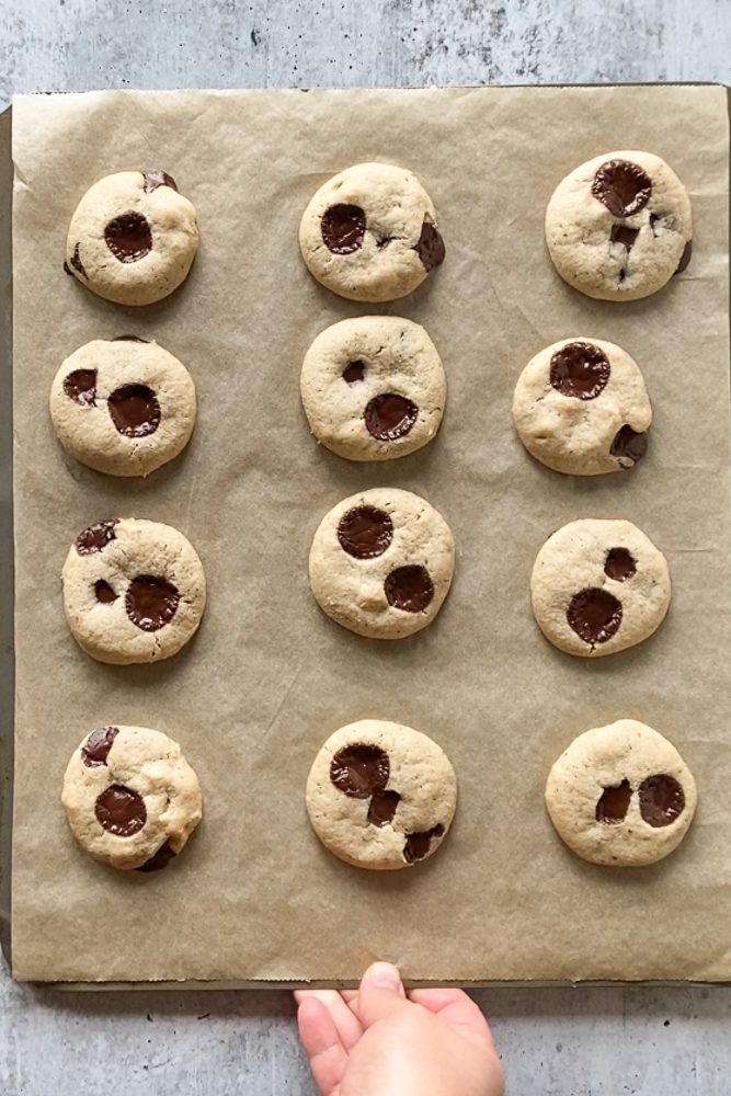 Tahini Chocolate Chip Macademia Nut Cookies baked on parchment lined baking sheet by Flora & Vino