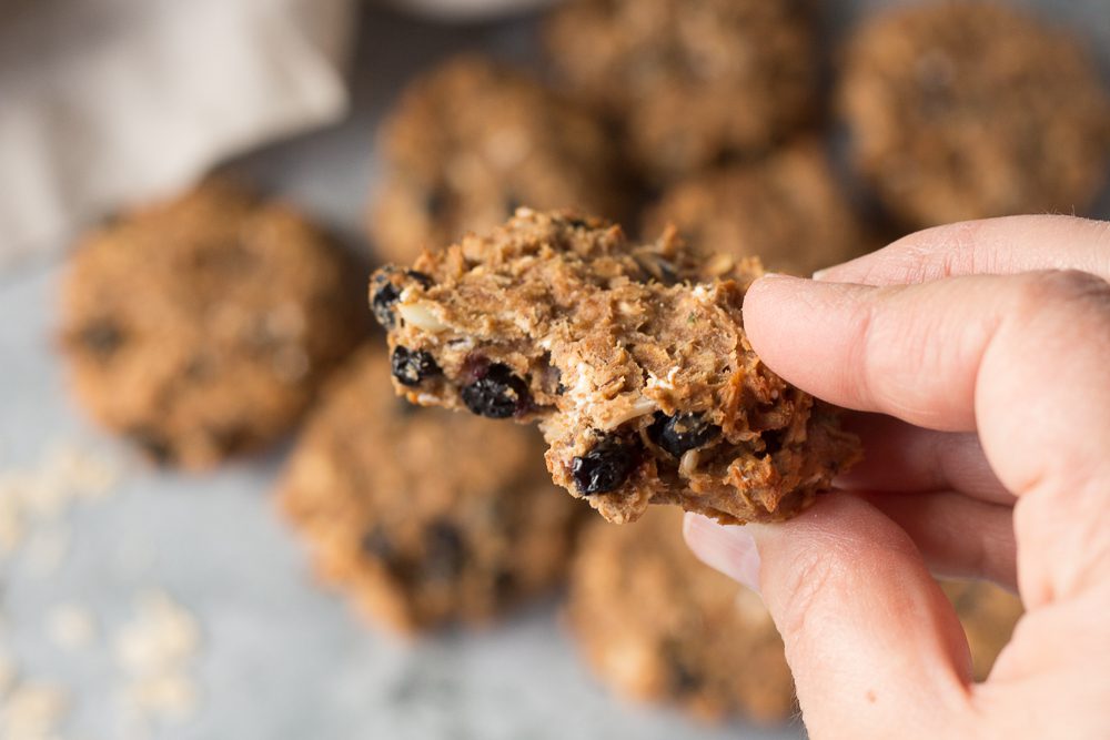 hand holding half of Blueberry Almond Protein Cookie by Flora & Vino