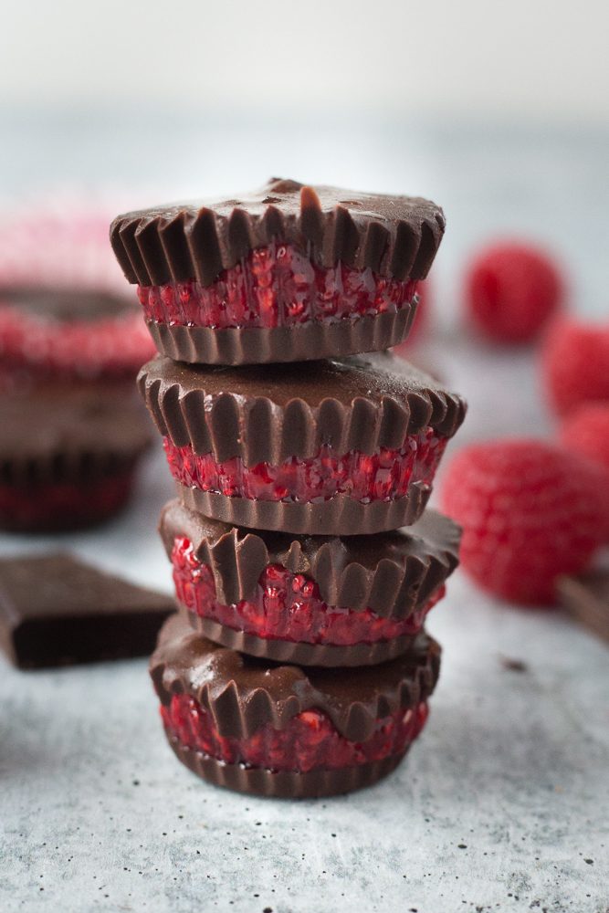 Chocolate Covered Raspberry Chia Cups stacked with raspberries and chopped chocolate by Flora & Vino