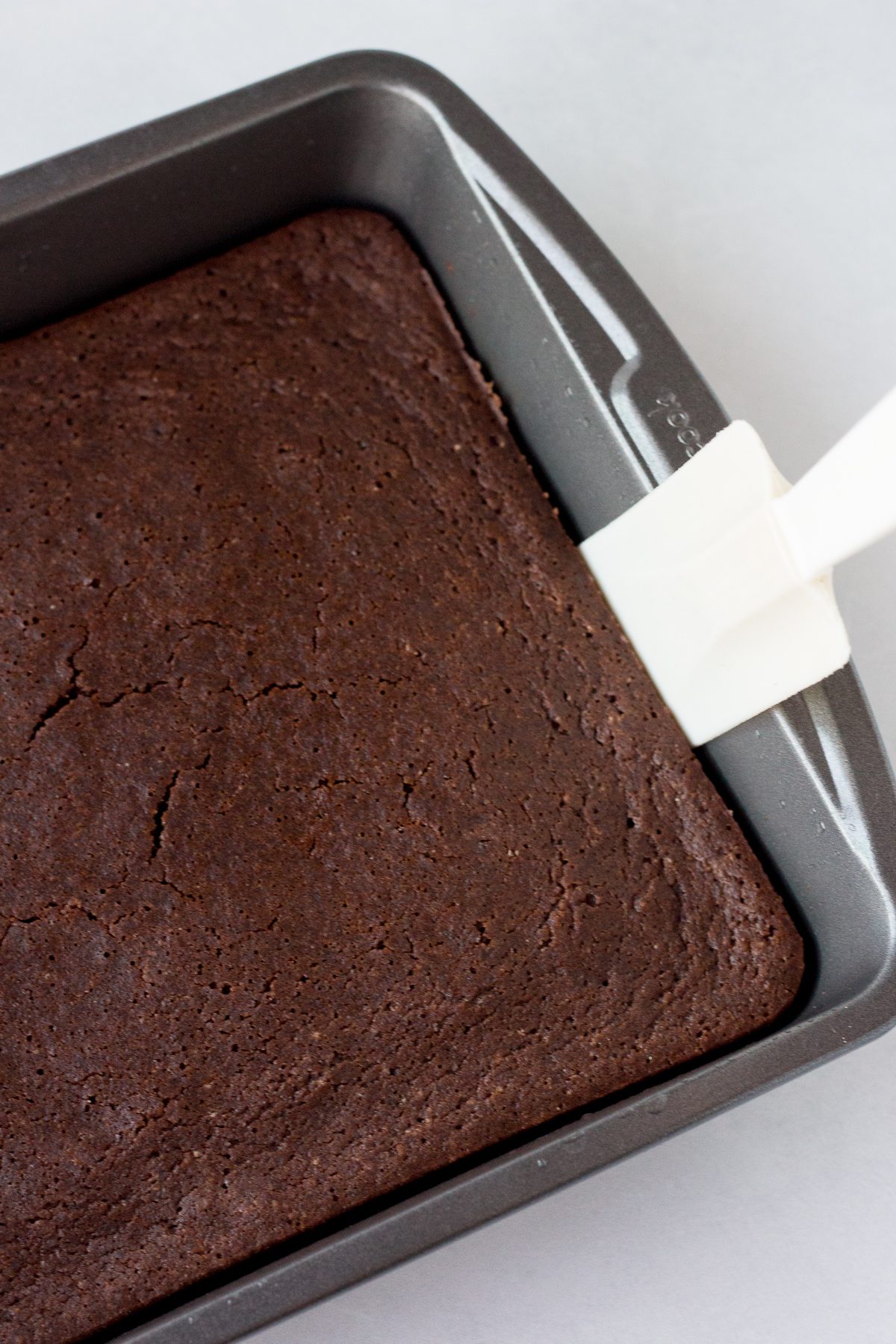 vegan chocolate cake baked in baking pan with spatula