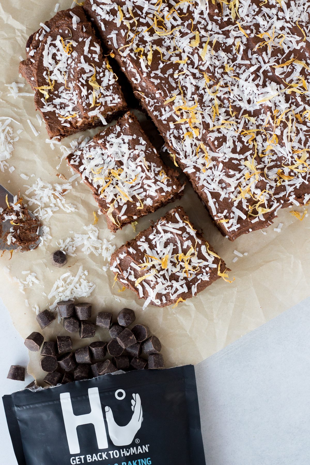 Vegan Chocolate Cake topped with sweet potato frosting and cut into squares on parchment paper 