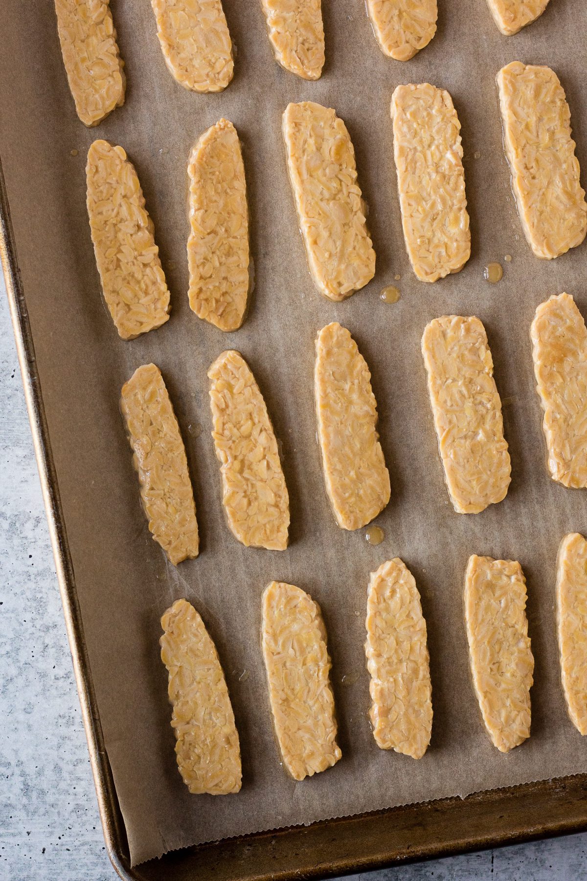 marinaded tempeh on baking sheet with parchment paper by Flora & Vino