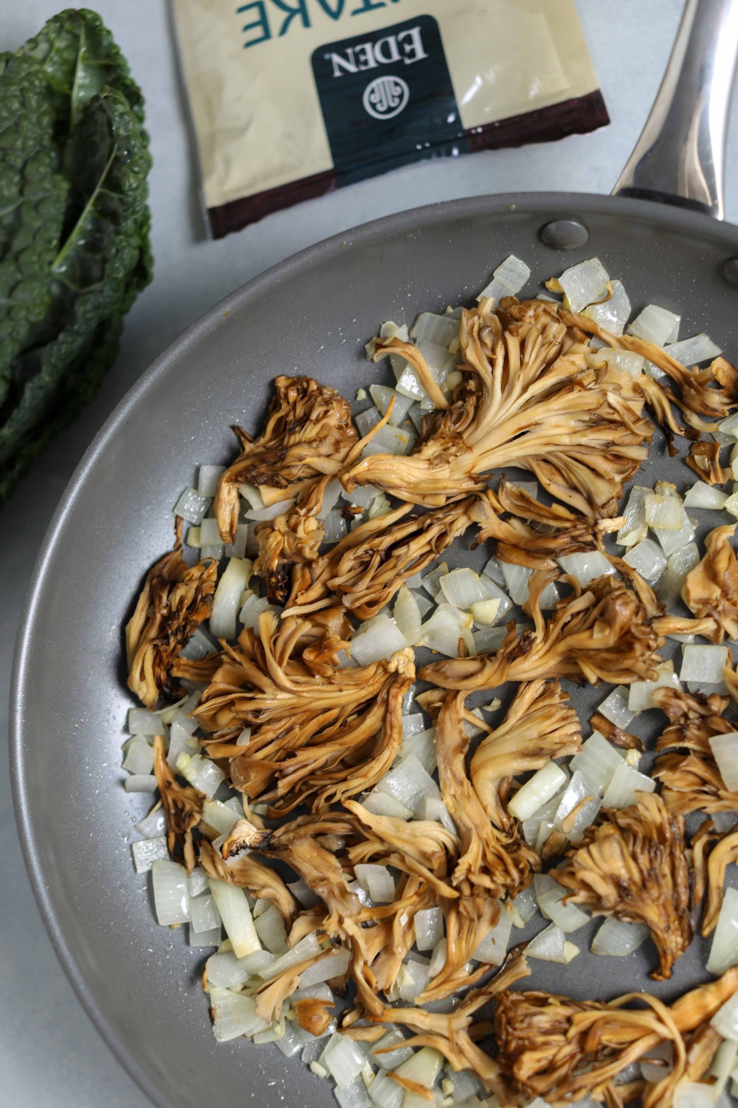 chopped onion and dried mushrooms in pan with kale on the side