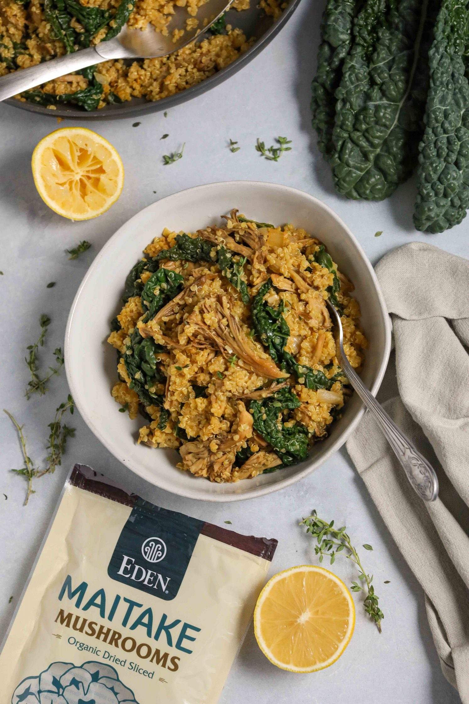 Kale Quinoa Mushroom Risotto served in bowl with lemon and scattered fresh thyme and spoons