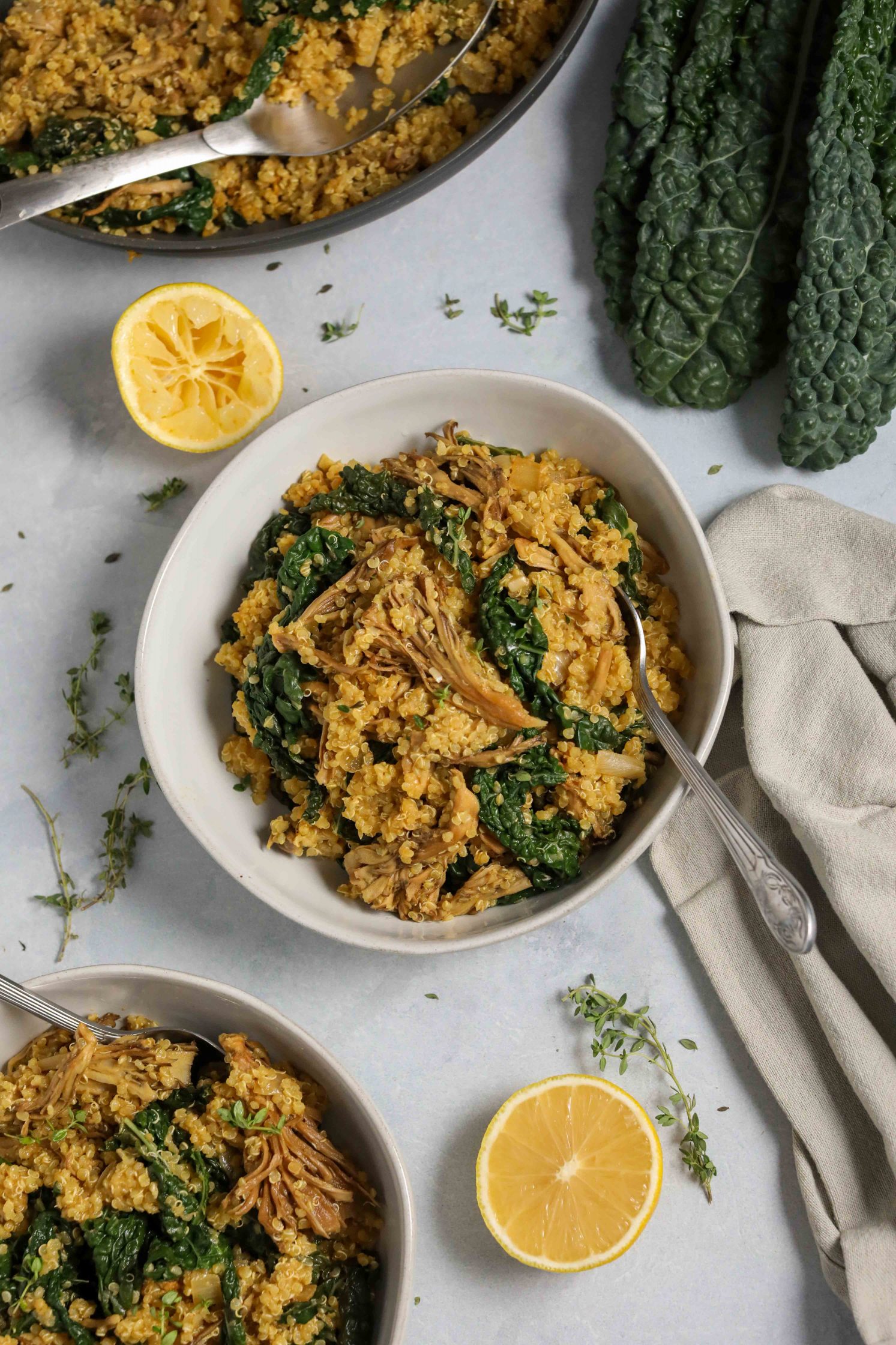 Kale Quinoa Mushroom Risotto served in bowl with lemon and scattered fresh thyme and spoons