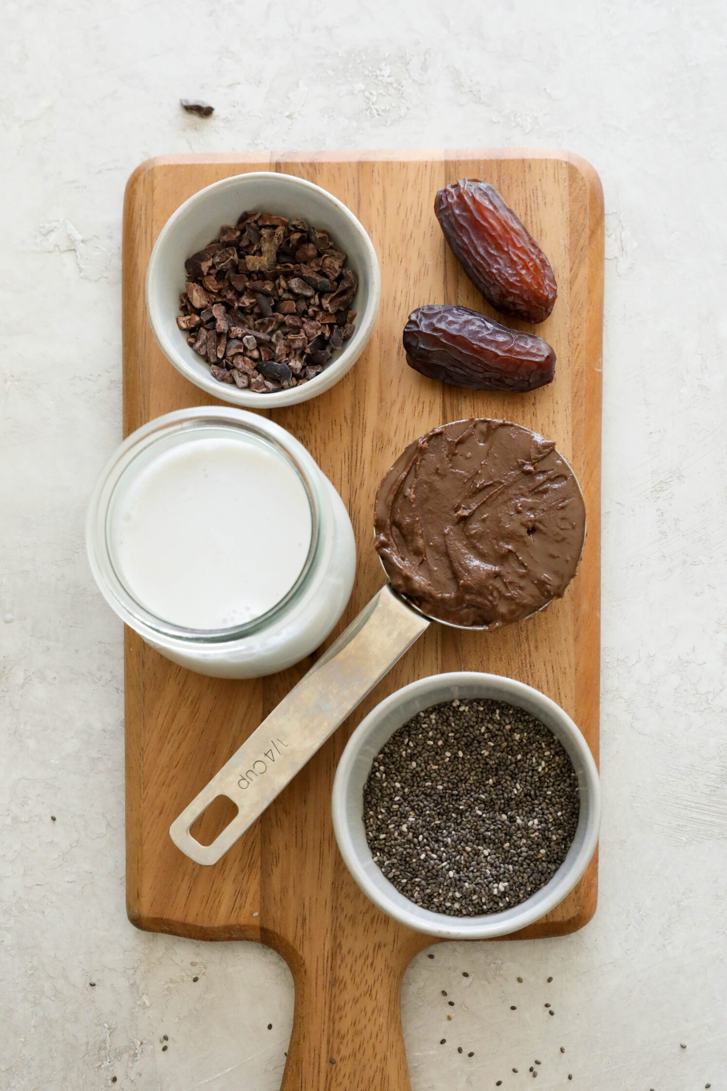 cacao nibs, Medjool dates, chocolate sunbutter, almond milk, and chia seeds on wooden board