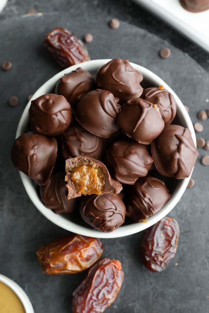 Vegan SunButter Date Caramels served in bowl with bite out of one by Flora & Vino