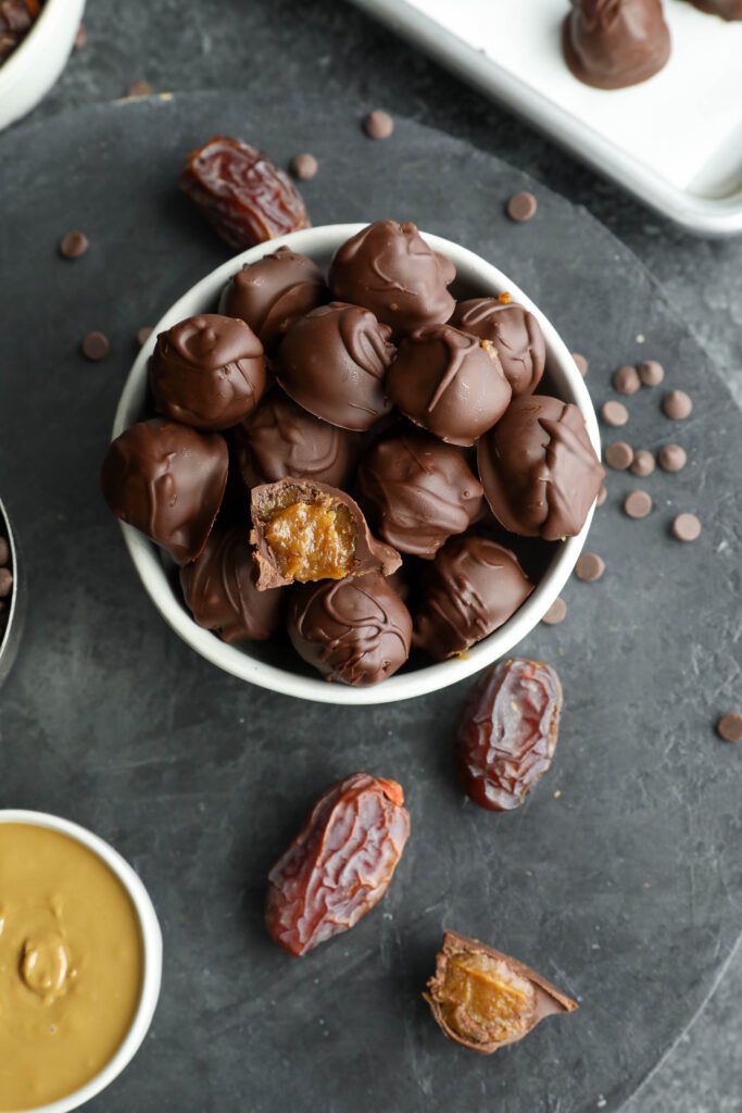 Vegan SunButter Date Caramels served in bowl with bite out of one by Flora & Vino