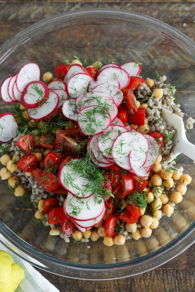 buckwheat, chickpeas, radishes, and tomatoes with dill in glass bowl