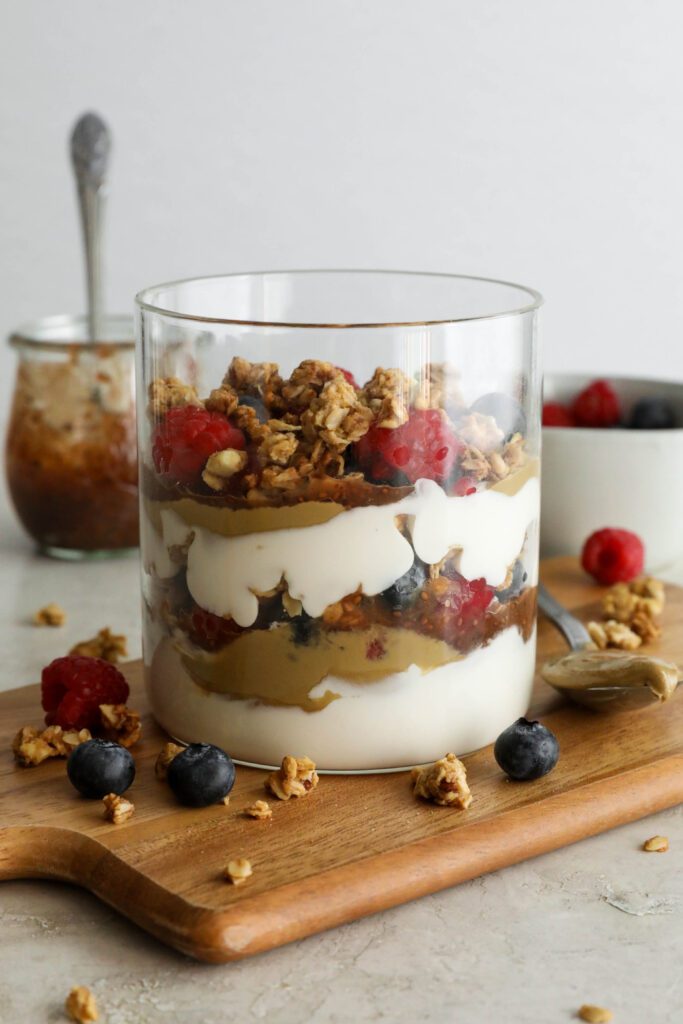 SunButter Berry Spring Parfait in glass jar on wooden board with berries and granola sattered